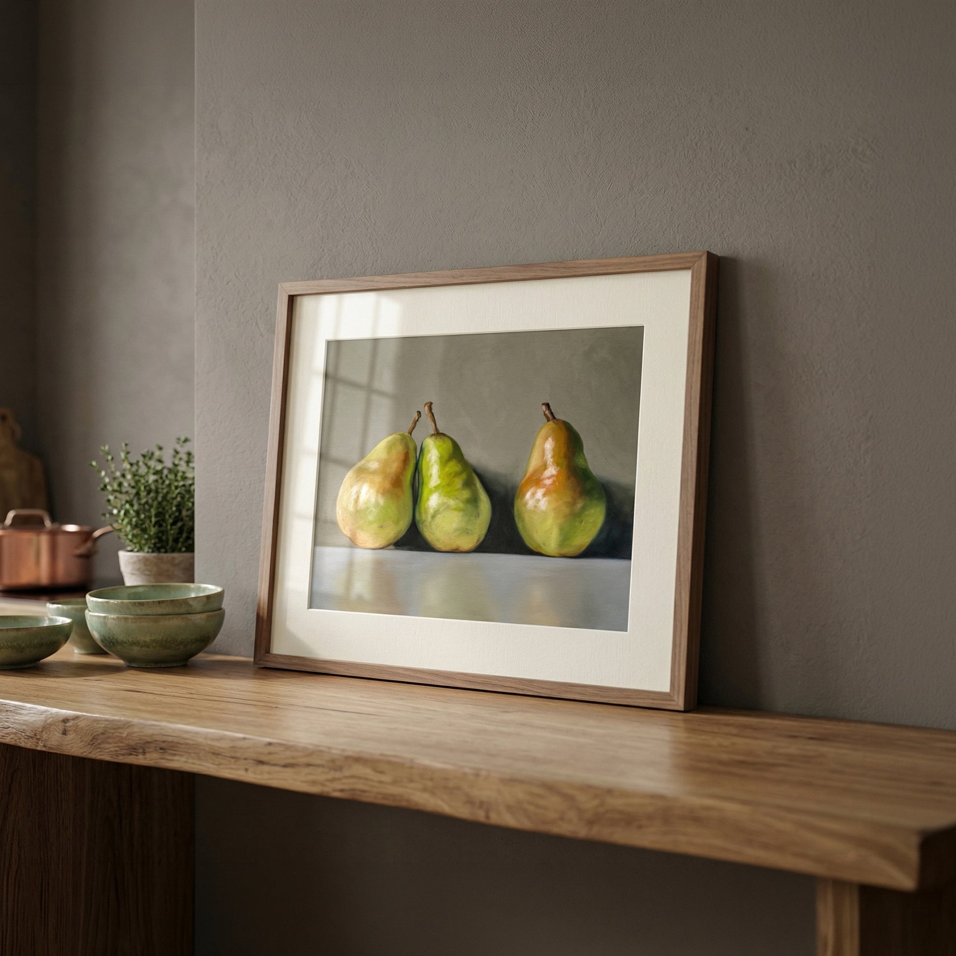 Fine art print of three green and yellow pears in a natural wood frame, displayed on a wooden shelf.