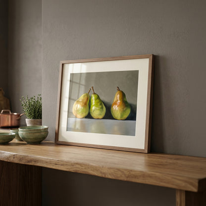 Fine art print of three green and yellow pears in a natural wood frame, displayed on a wooden shelf.