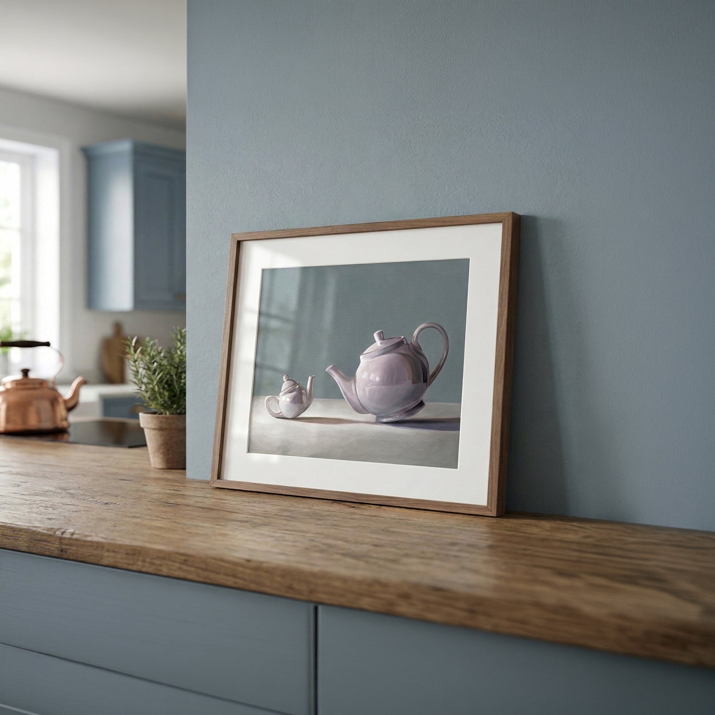Framed fine art print of a large and small lavender teapot on a light surface, displayed on a wooden counter.