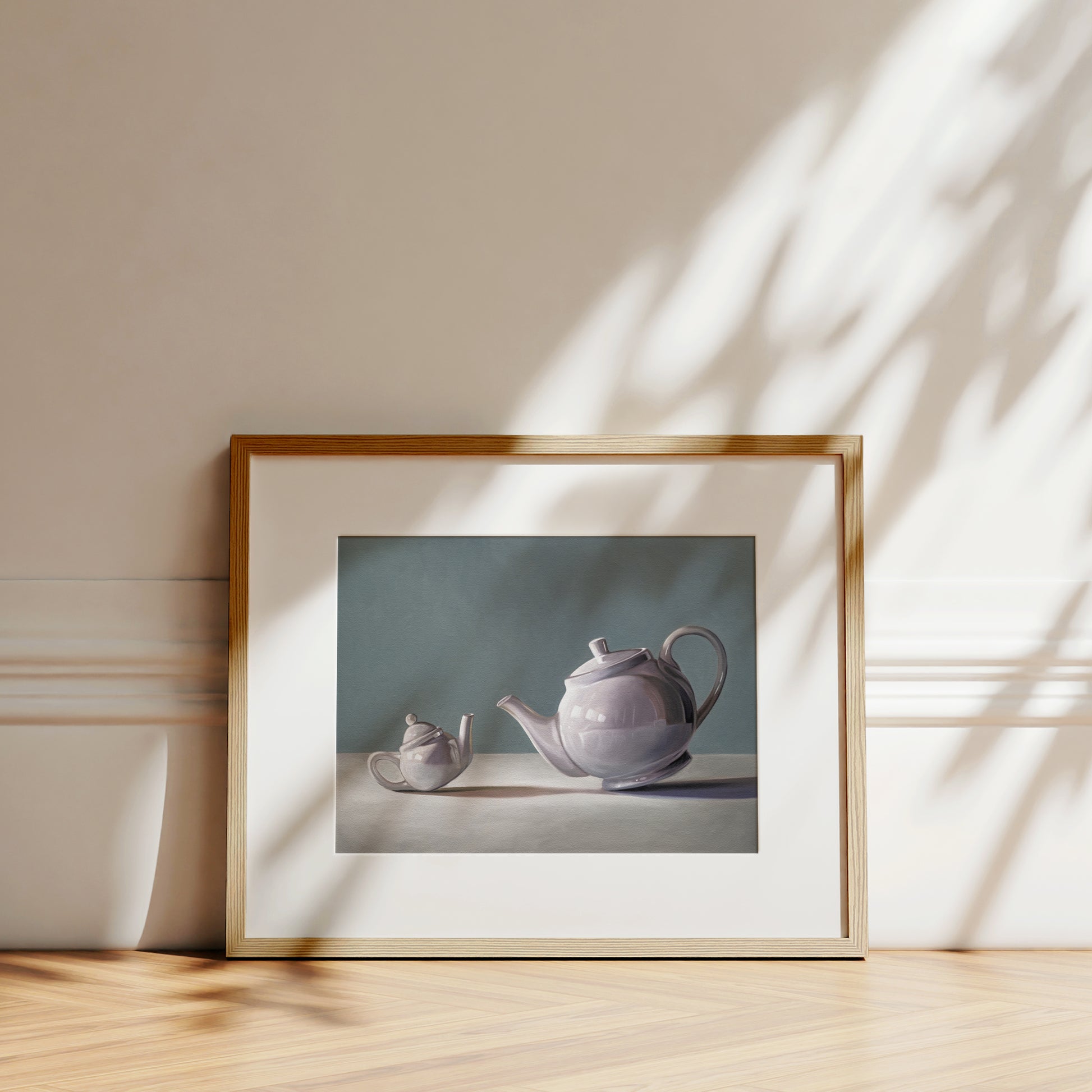 Fine art print of two lavender teapots on a white surface against a teal background, framed in light wood.