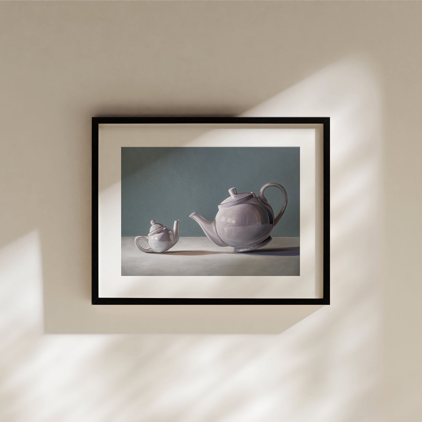Framed fine art print of two lavender teapots, one small and one large, on a white surface against a teal background.