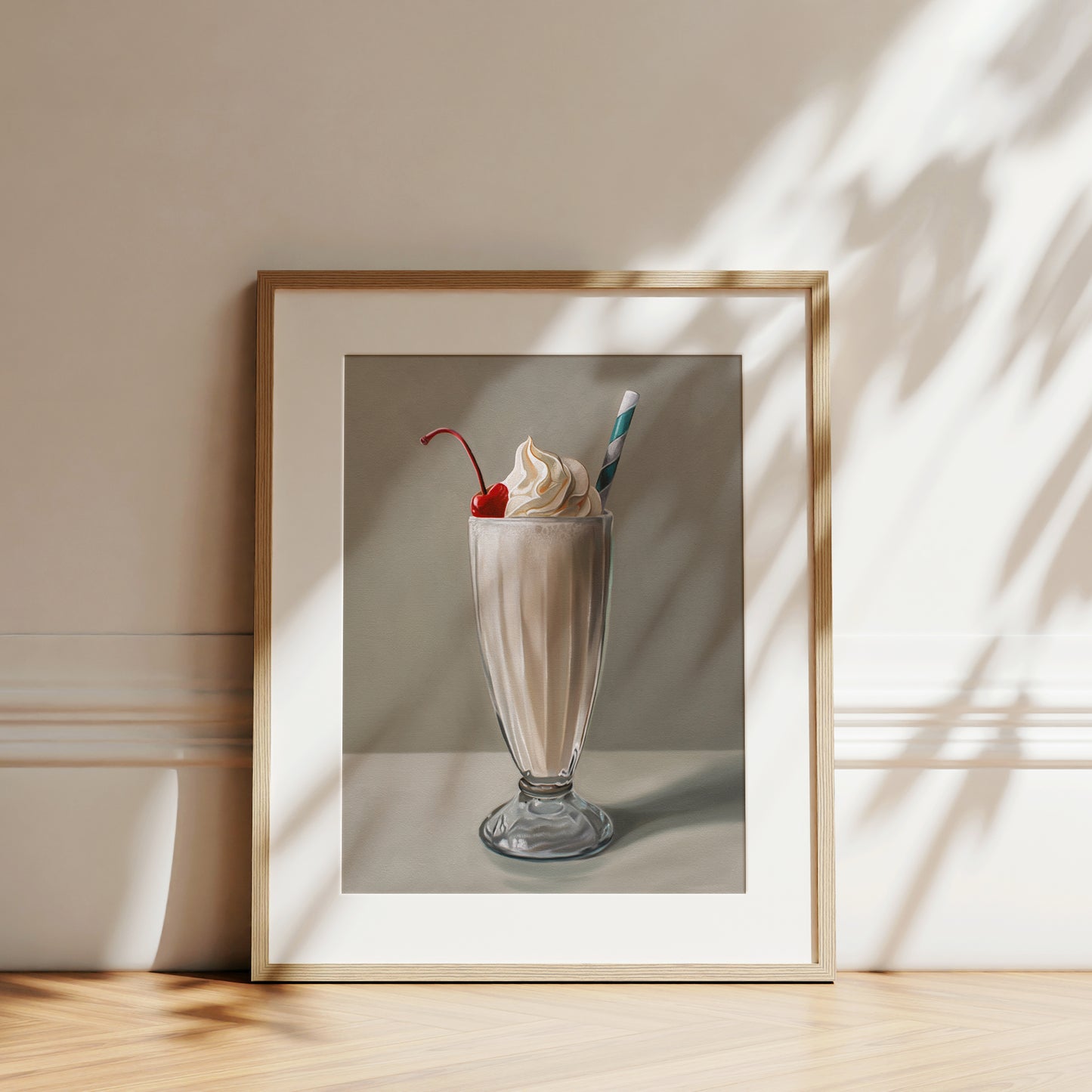 Vanilla milkshake fine art print in a light wood frame, featuring whipped cream, a cherry, and a striped straw.