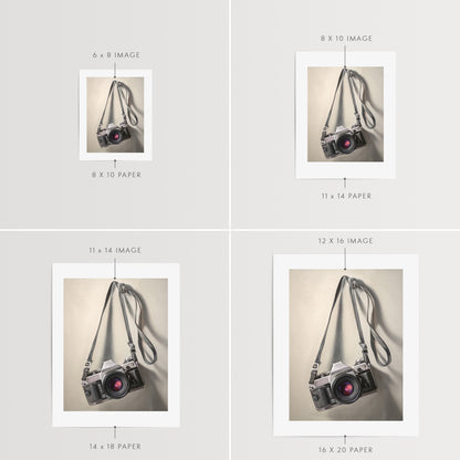 Vintage Film Camera Fine Art Print by Lauren Pretorius: a vintage 35mm camera hanging from its strap with some nice dramatic lighting.