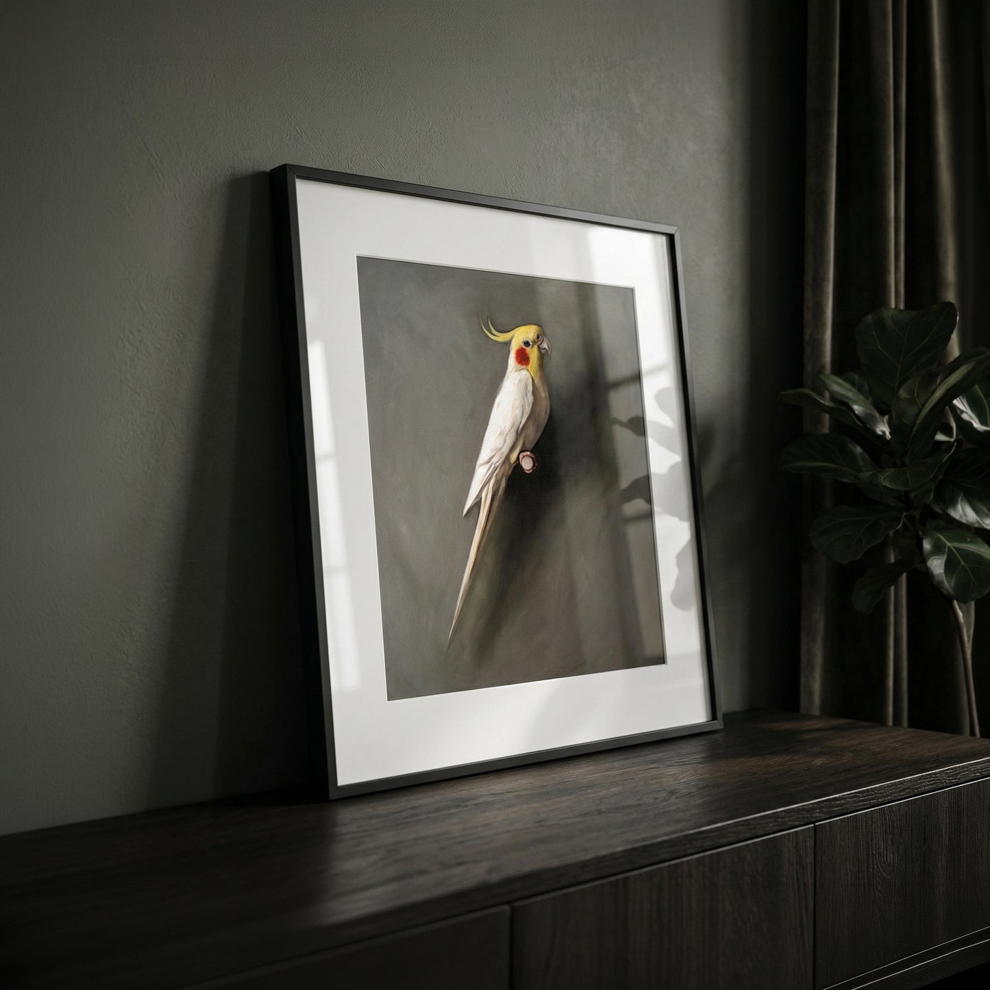 Framed fine art print of a white cockatiel with yellow crest, displayed on a dark wood cabinet.