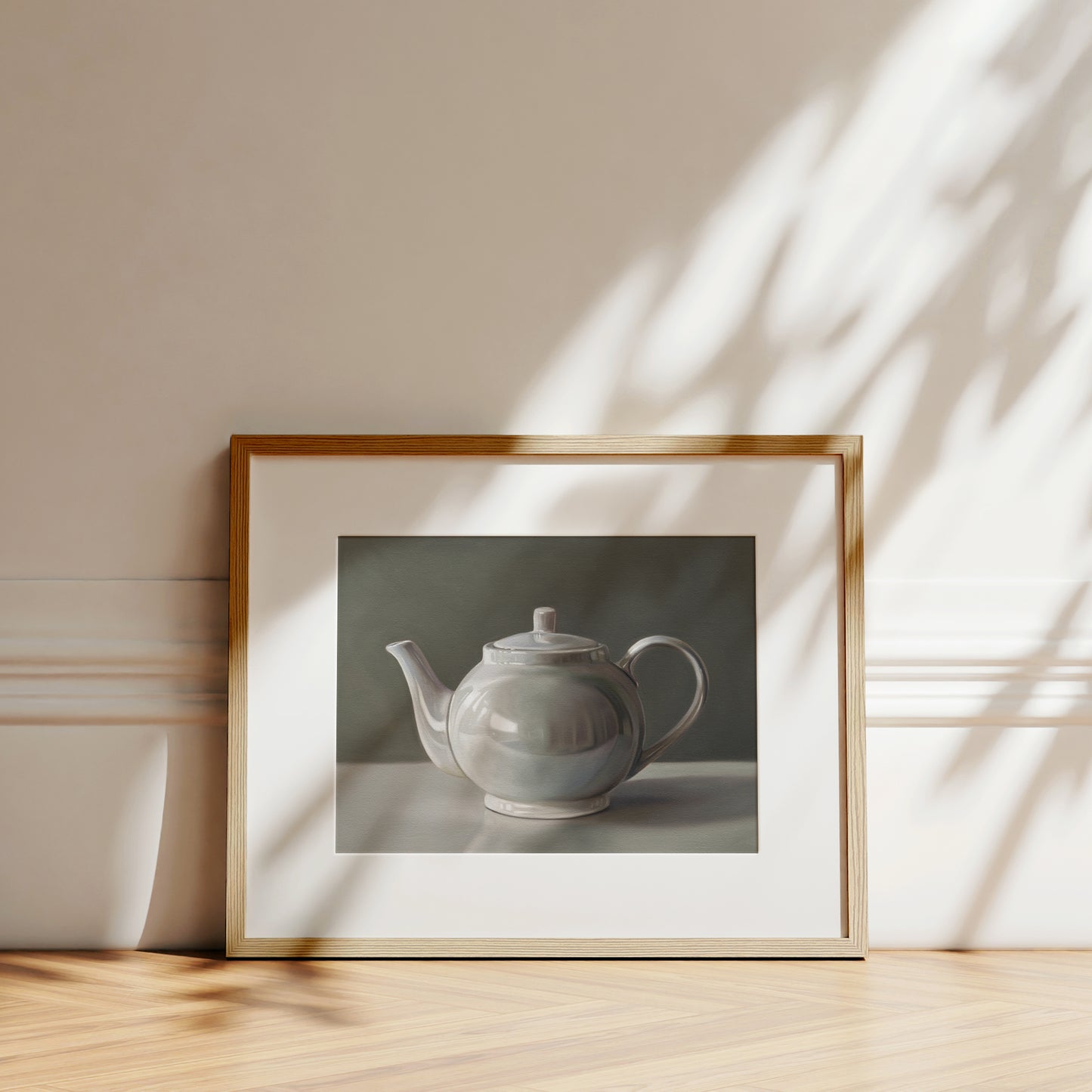 Fine art print of a white teapot with subtle reflections, framed in light wood.